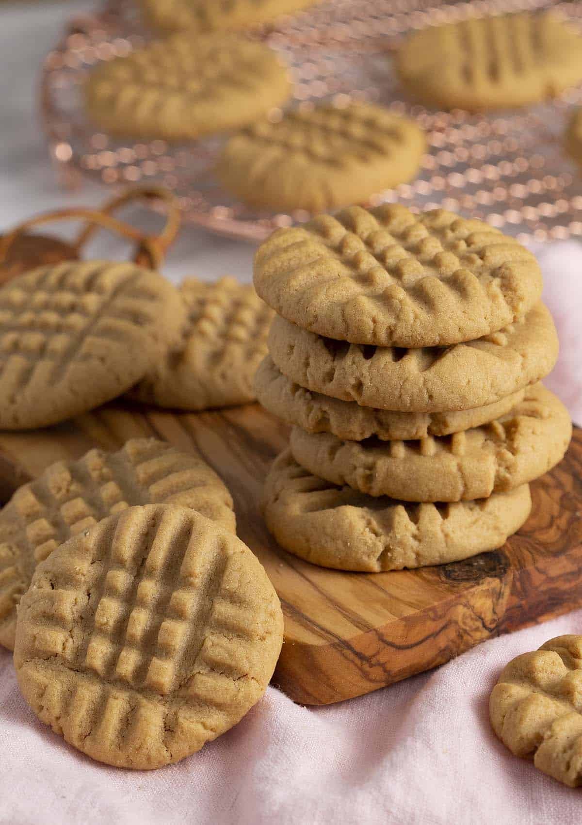 A tempting stack of homemade peanut butter cookies on a rustic wooden board, showcasing their classic criss-cross pattern and golden-brown edges.