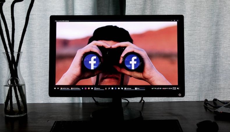 Person on monitor screen looking through Facebook binoculars hero image