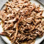 A flavorful pile of pulled pork served on a white plate.