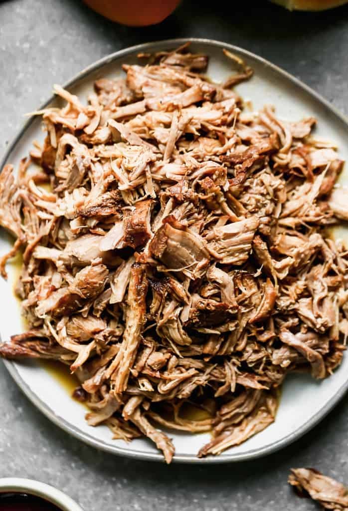 A flavorful pile of pulled pork served on a white plate.