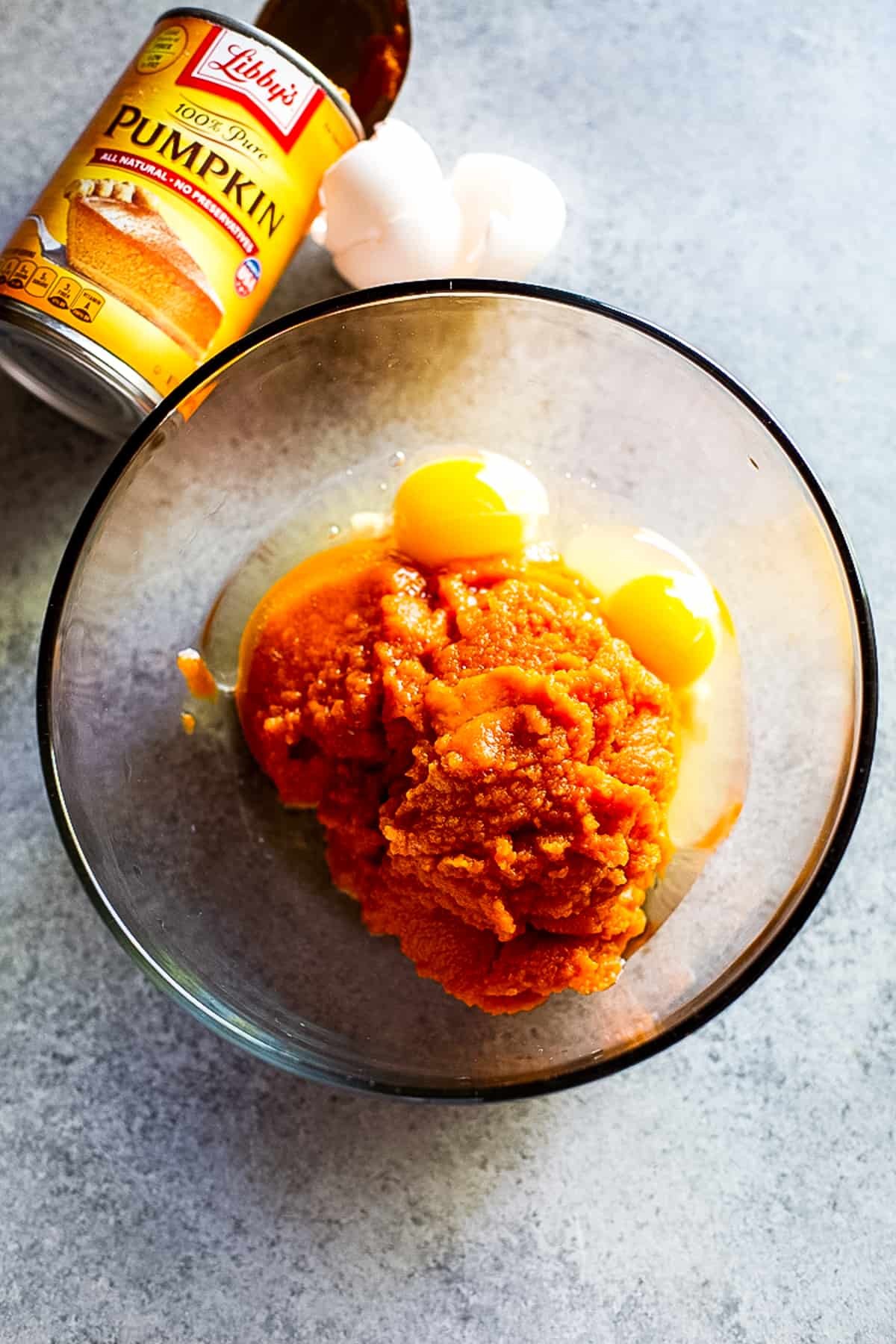 Ingredients for pumpkin pie batter in mixing bowls, showcasing pumpkin puree, eggs, sugar, and spices.