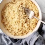 Close up of cooked quinoa in a white bowl, showcasing its fluffy texture.