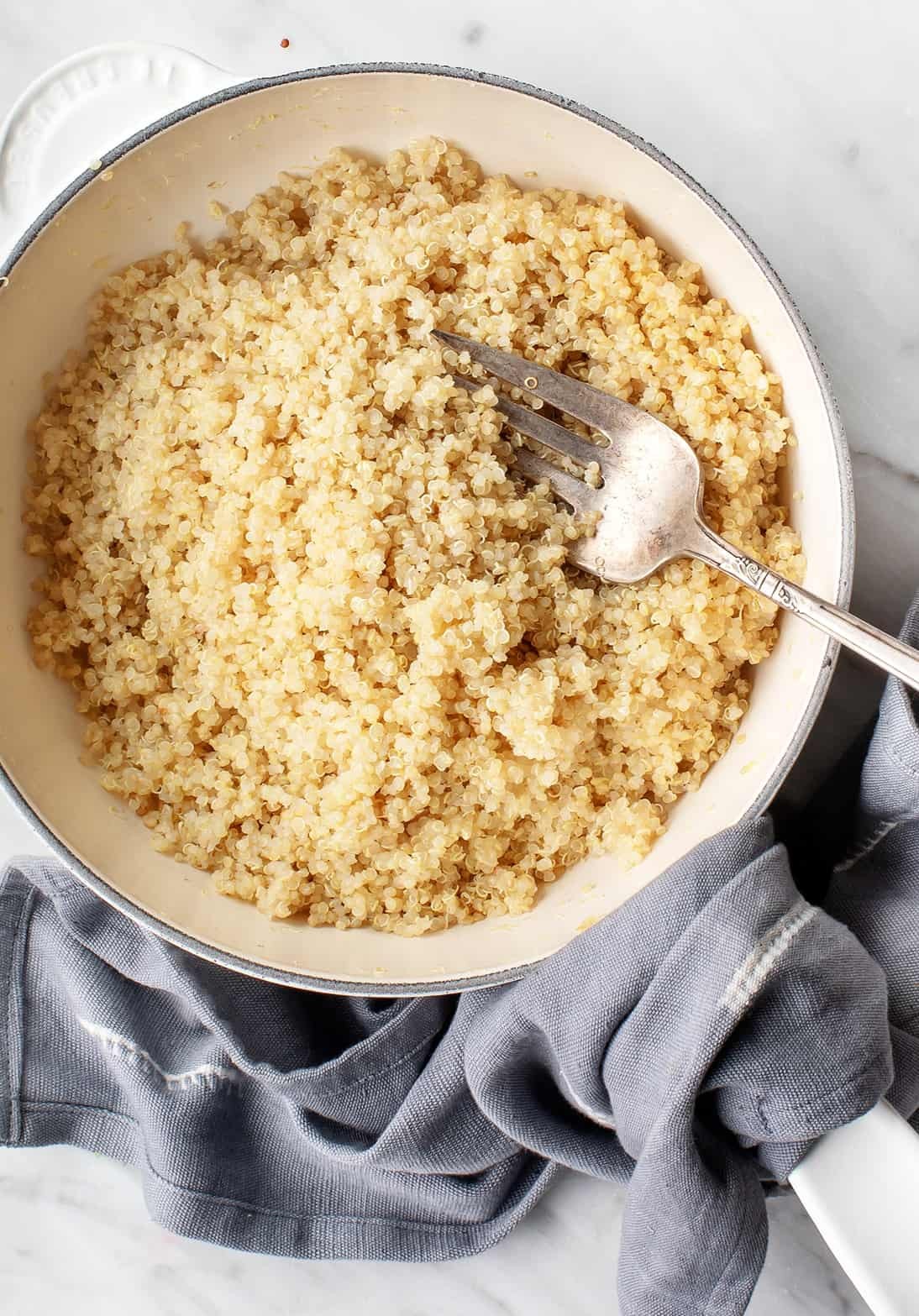 Close up of cooked quinoa in a white bowl, showcasing its fluffy texture.