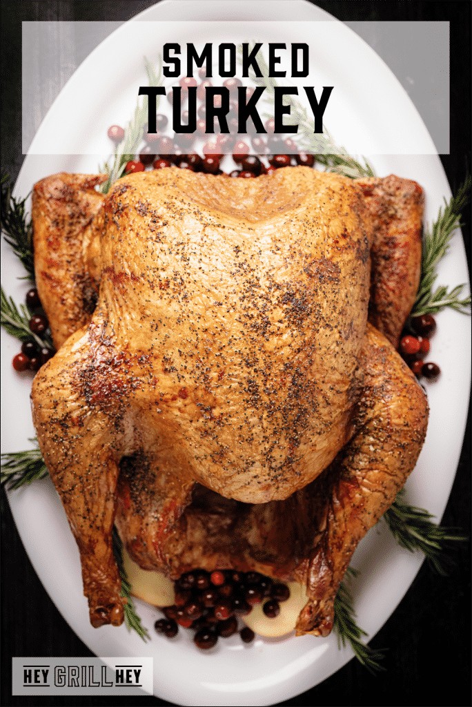 Whole smoked turkey presented on a platter, showcasing its rich, dark, and smoky exterior.