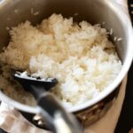 Perfectly cooked fluffy white rice in a saucepan, demonstrating how long rice takes to cook when using the stovetop method, with a spatula for serving.