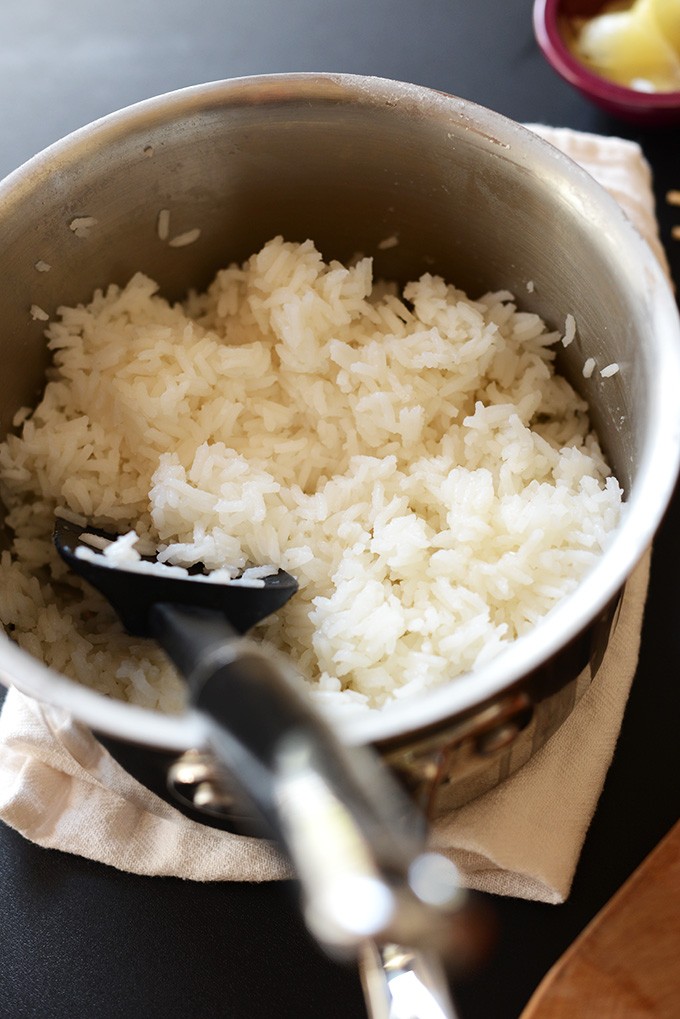 Perfectly cooked fluffy white rice in a saucepan, demonstrating how long rice takes to cook when using the stovetop method, with a spatula for serving.