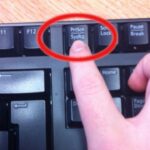 Pressing the Print Screen (PrtScn) key on a Windows keyboard to take a screenshot of the entire screen