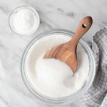 Granulated sugar and cornstarch in bowls, the two ingredients needed to make powdered sugar