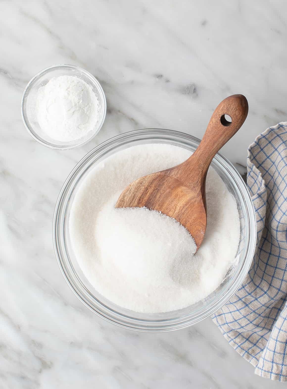 Granulated sugar and cornstarch in bowls, the two ingredients needed to make powdered sugar