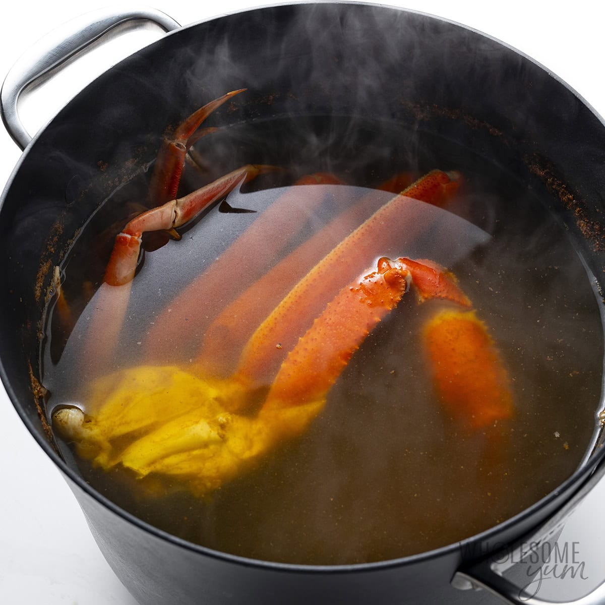 Boiled crab legs in a pot with seasonings.