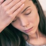 Woman holding her head with a headache after a night out drinking.