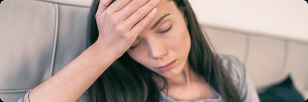 Woman holding her head with a headache after a night out drinking.