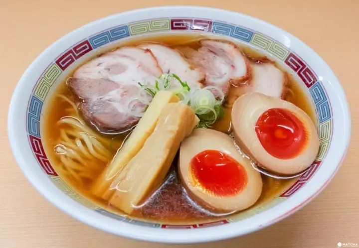 A steaming bowl of ramen, a staple in Japanese cuisine, offering a cost-effective and delicious meal.