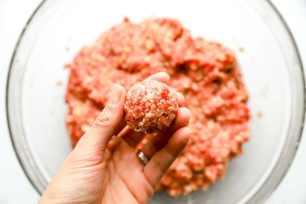 A formed meatball being held before being cooked.