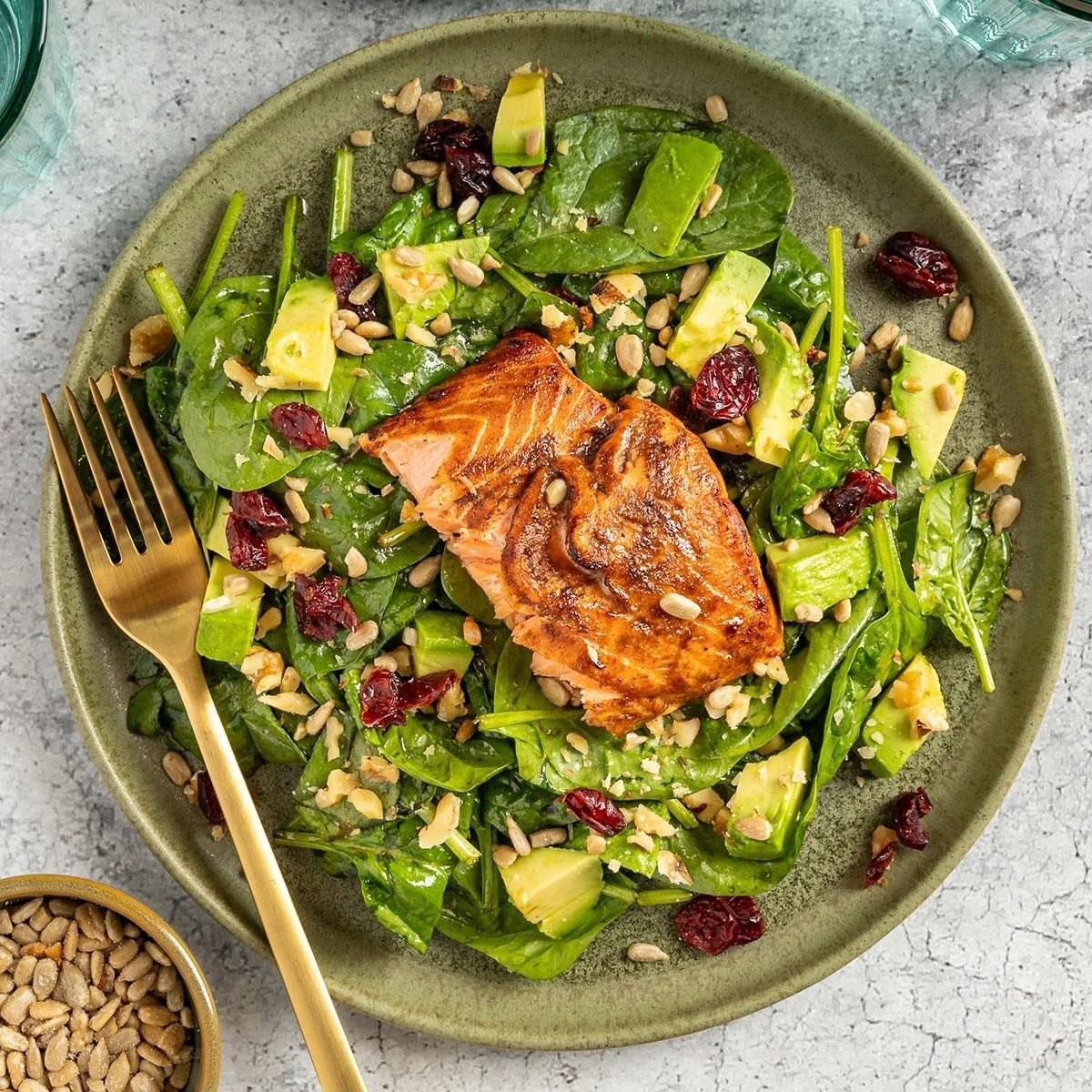 A vibrant salmon salad featuring mixed greens, cherry tomatoes, cucumber slices, and a balsamic vinaigrette