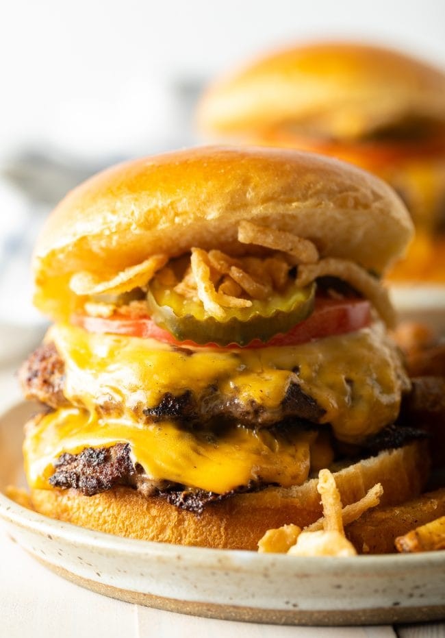 A collection of hamburger patties, some plain and some with cheese, ready to be served on buns with various toppings