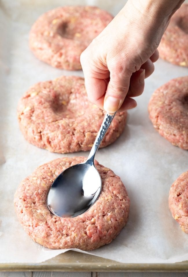 Close-up of hamburger patties cooking in a cast iron skillet, showing a crispy, seared exterior