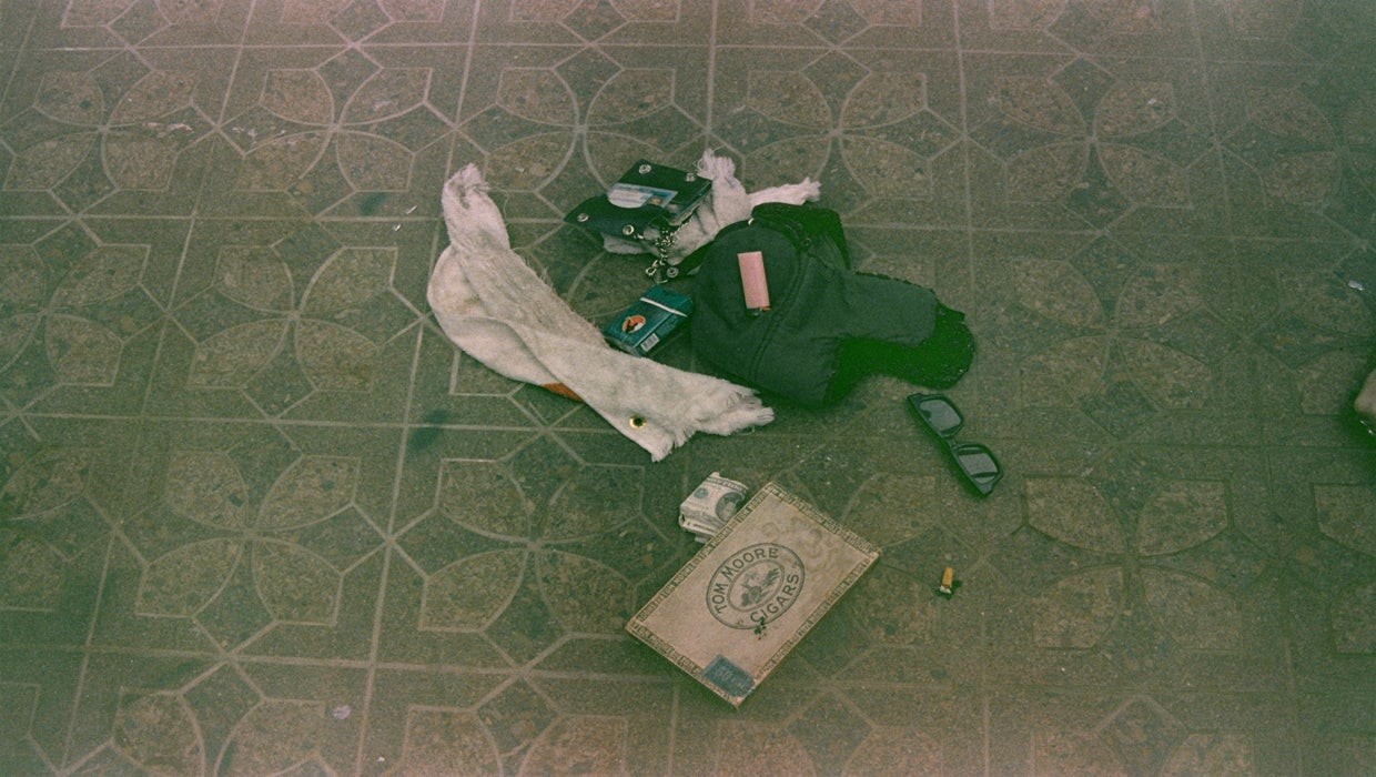 A cigarette lighter, a pack of cigarettes, a winter hat, cigarette butts, a wallet and sunglasses lie on the floor strewn around Cobain's heroin kit, depicting a sadly iconic rock and roll tragedy.