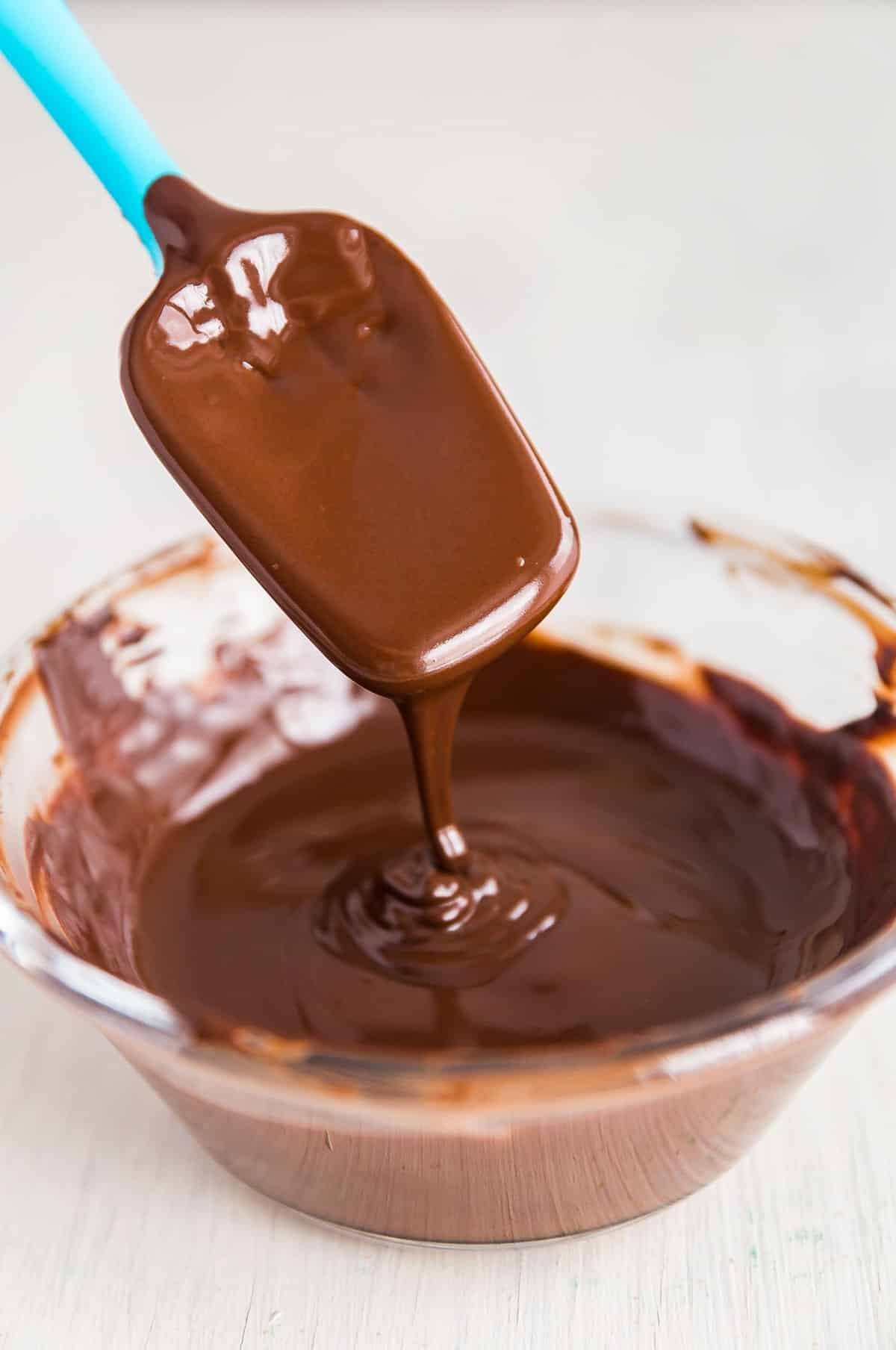 A glass bowl filled with smoothly melted chocolate, demonstrating the perfect consistency achieved through proper technique.