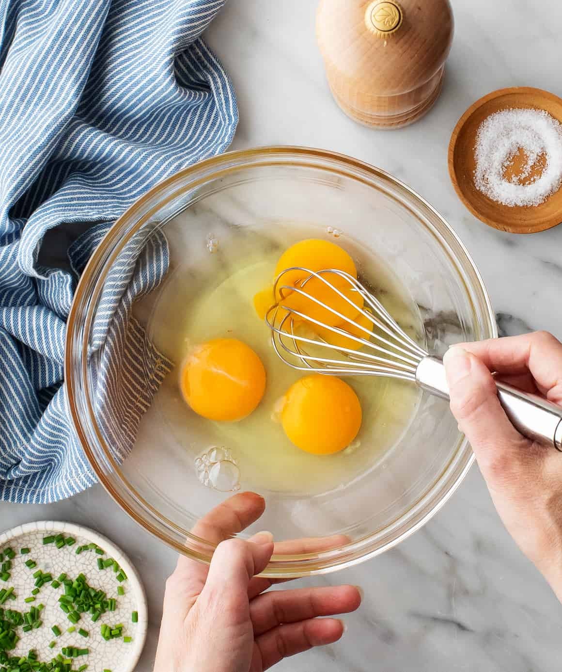 Hand whisking eggs in glass bowl