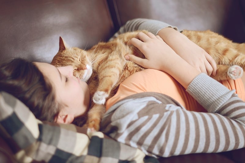 woman holding an orange cat on a sofa