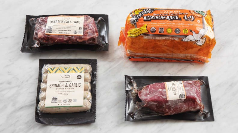 Thrive Market meat, sausages, and Ezekiel bread on marble surface
