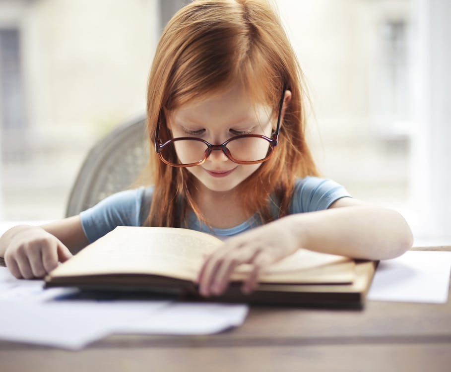 A young girl reading a book under a tree, symbolizing the theme of moral growth in "To Kill a Mockingbird."