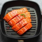 Cooked salmon fillet cut into four equal pieces in a cast iron grill pan.