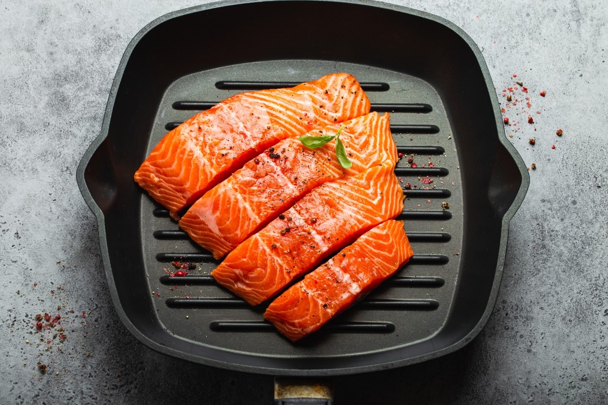 Cooked salmon fillet cut into four equal pieces in a cast iron grill pan.