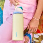 Yellow water bottle being held by a person wearing pink clothing