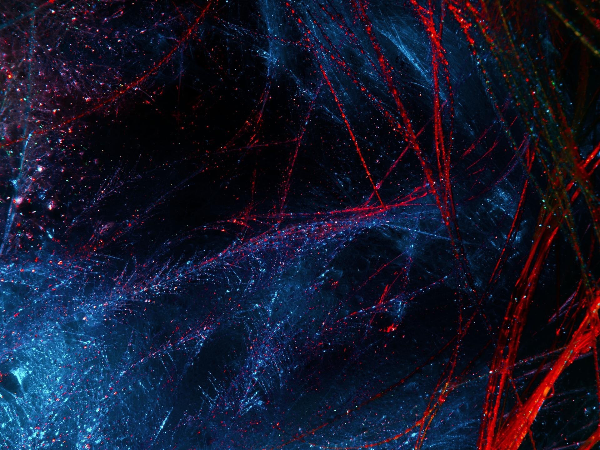 An abstract picture showing opposite points of red and blue light in patterns on a black background