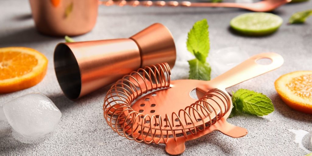 Close-up of a copper jigger and cocktail strainer