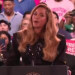 Kamala Harris speaking at a rally with a large crowd