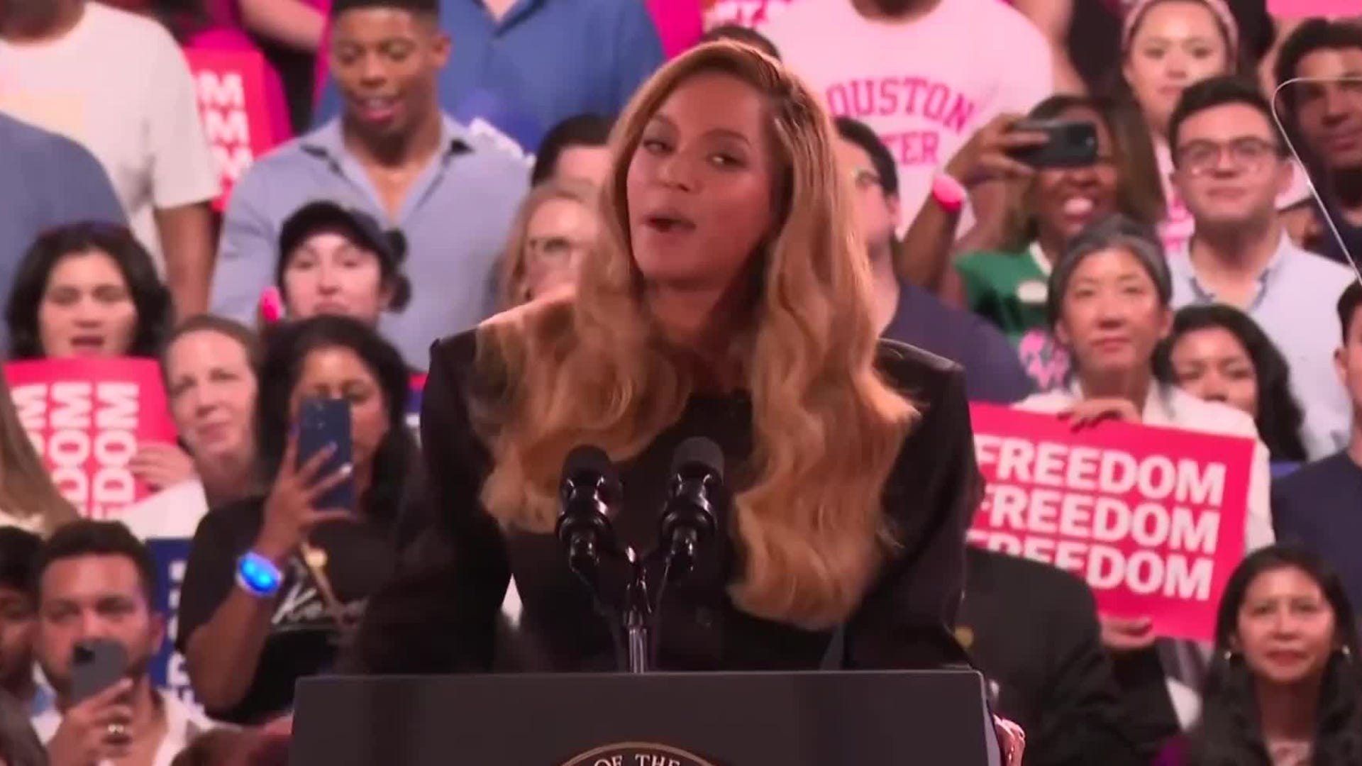 Kamala Harris speaking at a rally with a large crowd