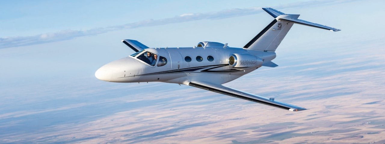 Cessna Citation Mustang flying over farmlands