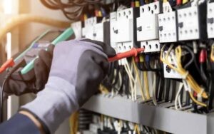 Electrician engineer tests electrical installations and wires on relay protection system. Adjustment of scheme of automation and control of electrical equipment.