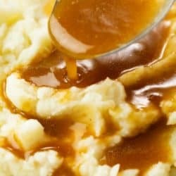 Brown gravy being drizzled over mashed potatoes, showcasing its rich color and texture