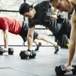 Man lifting weights with creatine supplement nearby