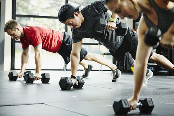 Man lifting weights with creatine supplement nearby