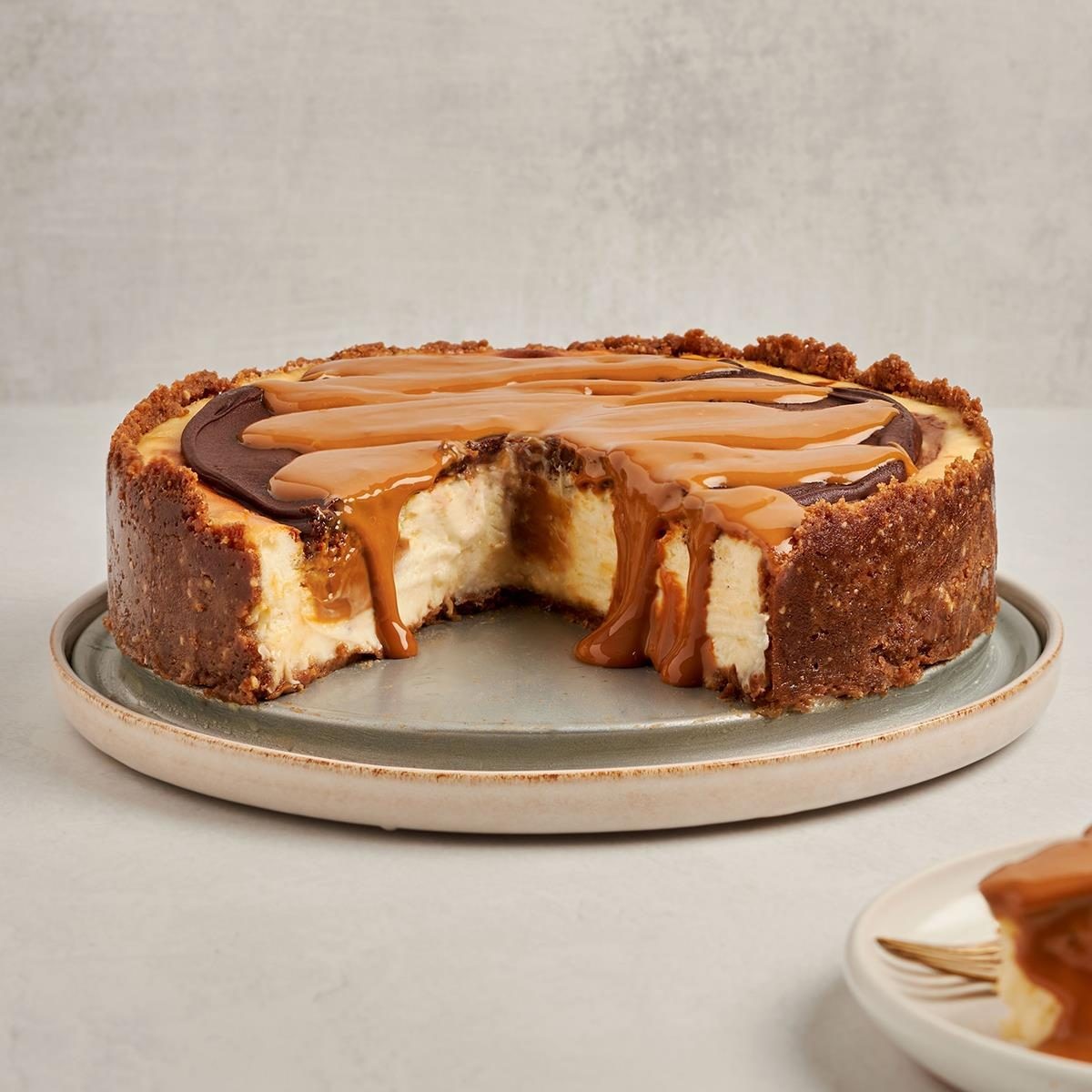 Dulce de Leche Cheesecake featuring rich cream cheese filling with swirls of dulce de leche atop a spiced gingersnap and walnut crust