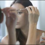 Woman washes her face with cleanser and cotton pads after microblading.