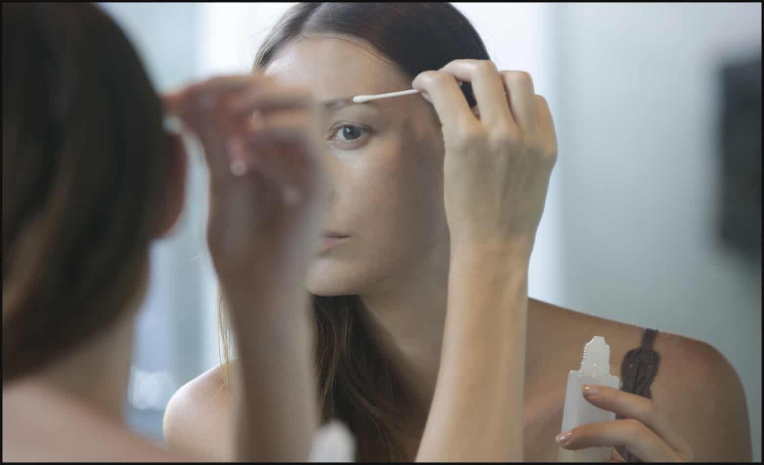 Woman washes her face with cleanser and cotton pads after microblading.