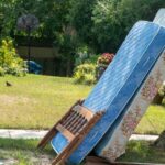 A mattress, box spring, and bed frame on a curb in front of a home for junk removal