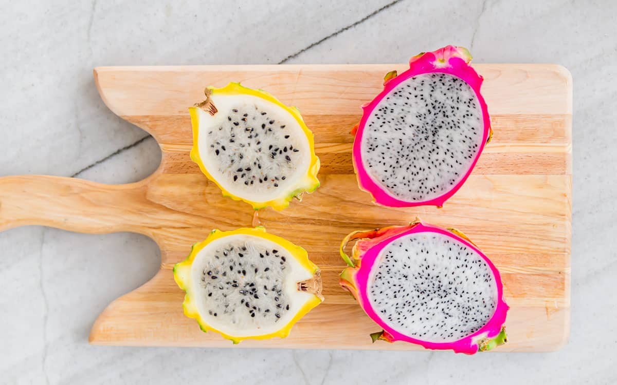 Dragon fruit sliced in half, revealing the white flesh and black seeds