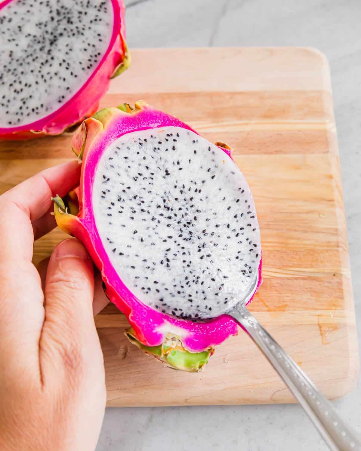Scooping dragon fruit flesh out of the peel with a spoon