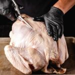 Prepared turkey on a cutting board, ready for spatchcocking.