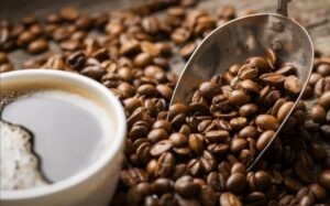 Person holding a cup of espresso with steam rising, set against a warm, inviting background