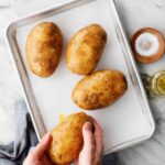 Russet potatoes being prepped for baking with olive oil and salt