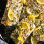 Skillet filled with fully cooked mahi mahi fillets cooked in a lemon butter sauce and garnished with fresh parsley.