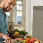 Man in kitchen making salad.